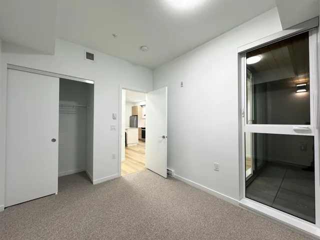 Unfurnished bedroom featuring light carpet, a closet, and freestanding refrigerator