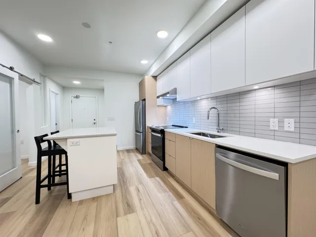 Kitchen featuring modern cabinets, white cabinetry, a kitchen island, appliances with stainless steel finishes, and light wood-style flooring