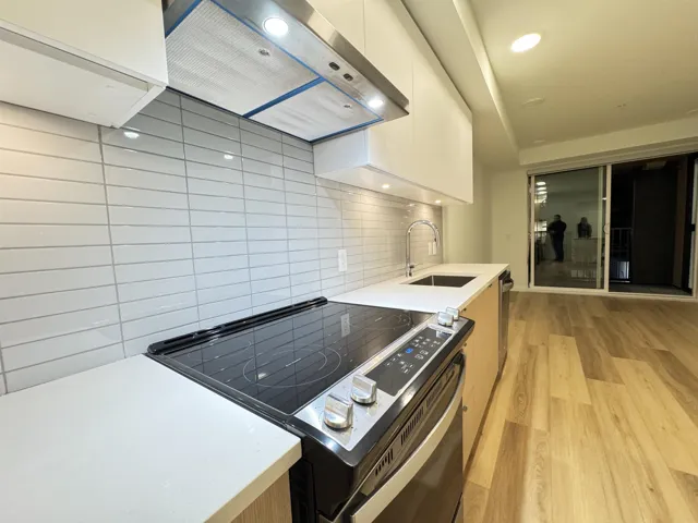 Kitchen featuring electric stove, ventilation hood, light wood-style flooring, modern cabinets, and white cabinetry