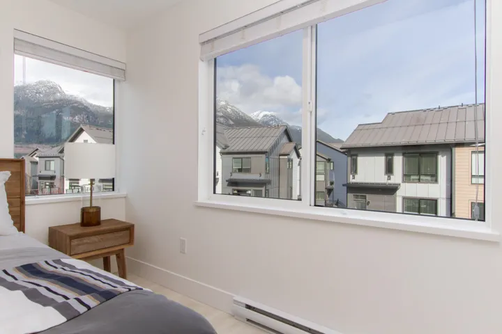 Bedroom featuring a baseboard heating unit, wood finished floors, baseboards, and a residential view
