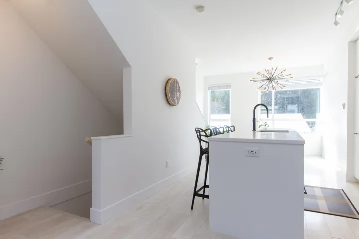 Kitchen with a center island with sink, a sink, an inviting chandelier, light countertops, and baseboards