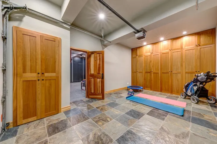 Spacious room featuring variegated stone tile flooring, extensive wood cabinetry, recessed ceiling lighting, and a wood-paneled door