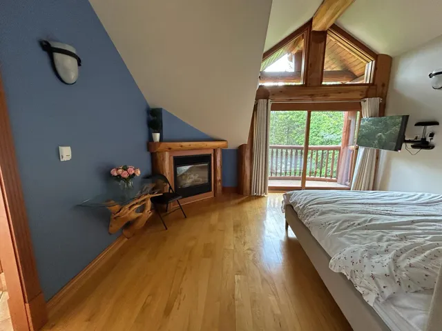 Bedroom with a glass covered fireplace, wood finished floors, and access to exterior