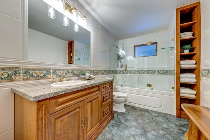 Full bath with tile walls, vanity, and shower / washtub combination