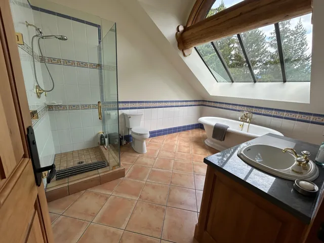 Full bath featuring a shower stall, a skylight, wainscoting, vanity, and tile patterned floors