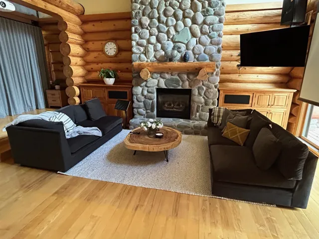 Living room with a stone fireplace and wood finished floors