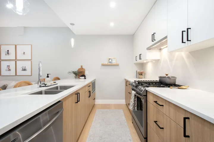Kitchen featuring appliances with stainless steel finishes, light countertops, a sink, and under cabinet range hood