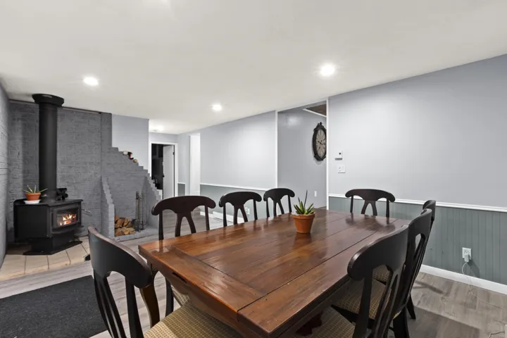 Dining room with a wood stove, light wood-style floors, recessed lighting, and wainscoting