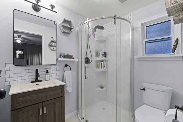 Full bathroom featuring vanity, a stall shower, and backsplash