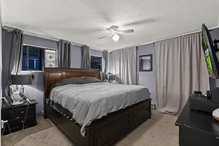 Bedroom featuring light colored carpet, a textured ceiling, and ceiling fan