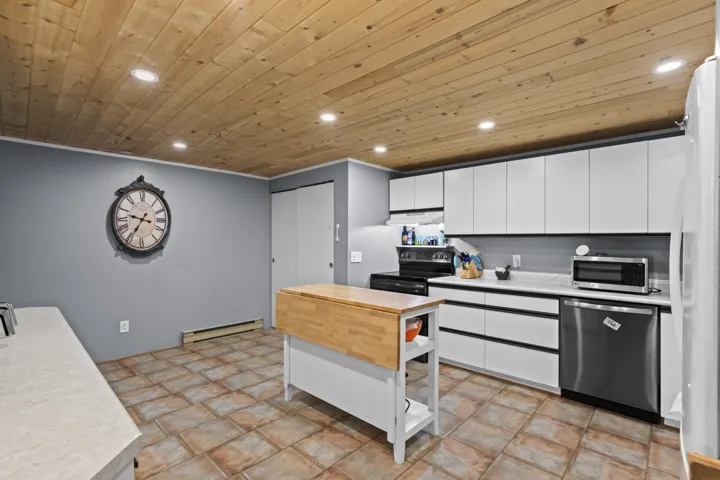 Kitchen featuring light countertops, white cabinets, appliances with stainless steel finishes, recessed lighting, and a baseboard radiator