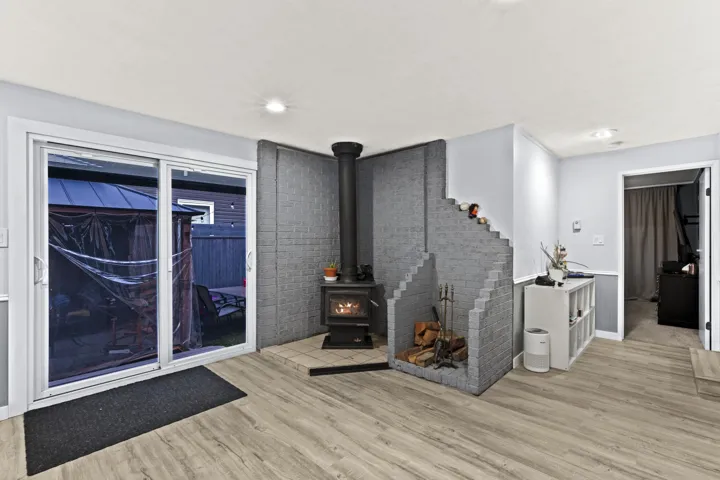 Living room with light wood-type flooring, a wood stove, and recessed lighting