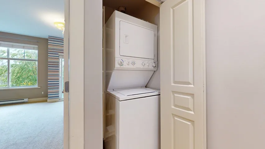 Laundry room featuring carpet, stacked washer / dryer, and baseboard heating