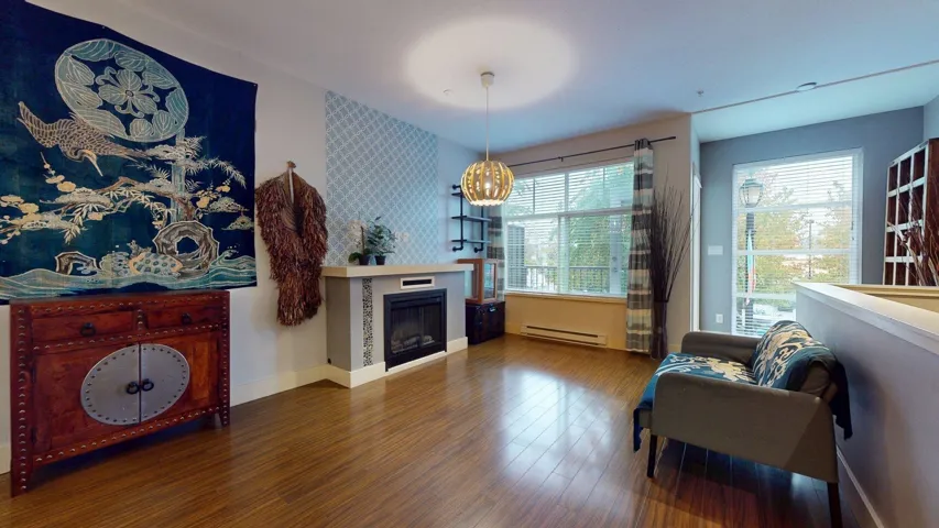 Living area with a fireplace, wood finished floors, and baseboard heating