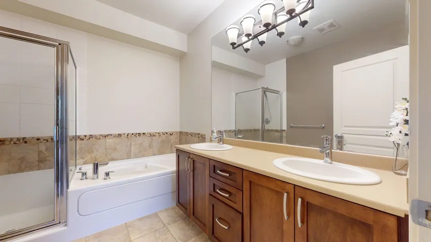Full bathroom featuring a bath, a shower stall, double vanity, and light tile patterned floors