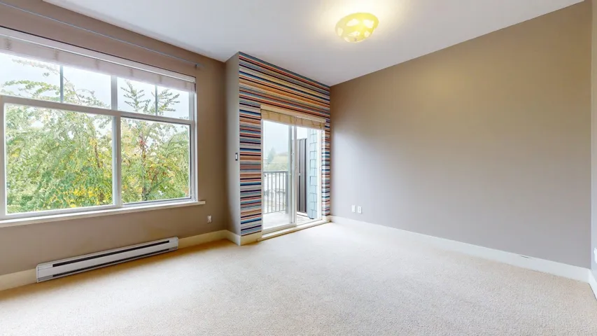 Carpeted spare room with a baseboard radiator and baseboards