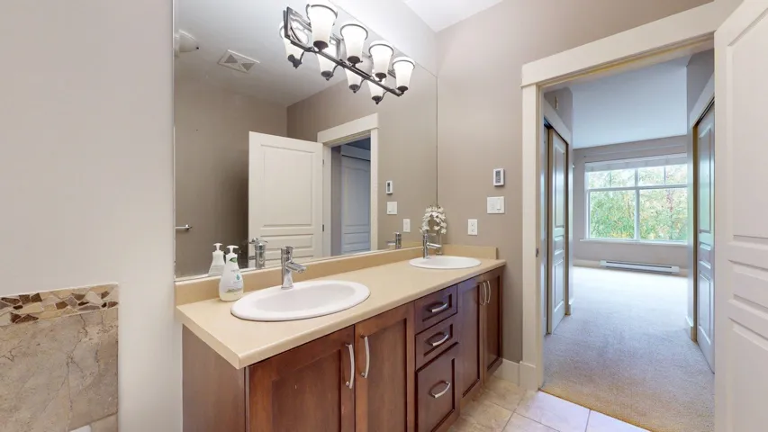 Bathroom with double vanity, light carpet, light tile patterned flooring, and a baseboard radiator