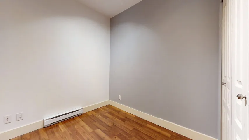 Unfurnished room featuring a baseboard radiator and wood finished floors