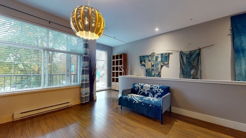 Living area featuring a baseboard heating unit and wood finished floors