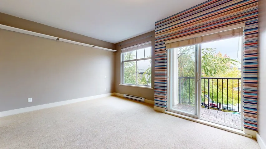 Carpeted empty room with baseboards and a baseboard heating unit
