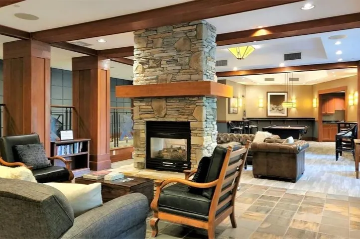Living area featuring beam ceiling, a stone fireplace, and recessed lighting