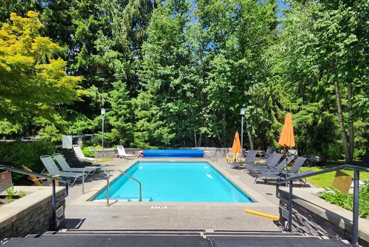 Community pool featuring a patio area and view of wooded area