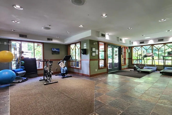Workout area featuring stone tile floors, recessed lighting, wainscoting, and french doors