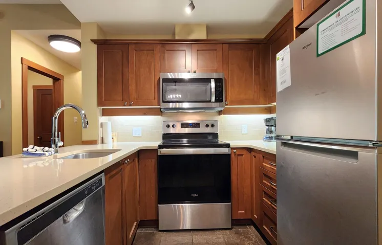 Kitchen with appliances with stainless steel finishes, decorative backsplash, brown cabinets, and a peninsula