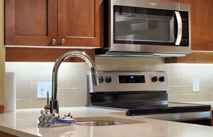 Kitchen view of appliances with stainless steel finishes, tasteful backsplash, and brown cabinets