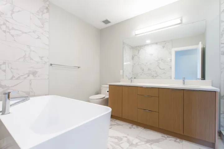 Ensuite Bathroom with visible vents, a soaking tub, marble finish floor, double vanity, and a sink