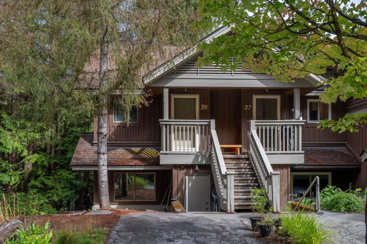 Multi-level facade with wood siding, gabled rooflines, and a prominent exterior staircase