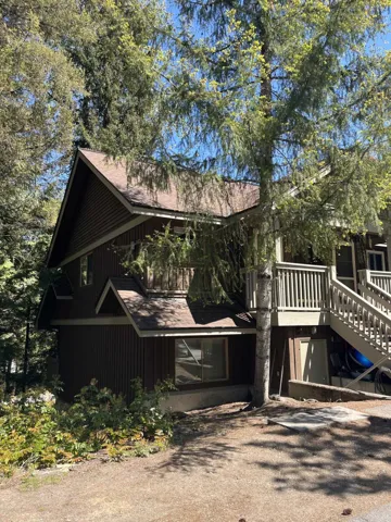 Multi-level exterior with dark vertical siding, multiple gables, and a prominent deck with railings