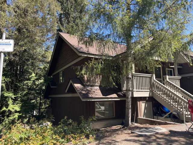 Multi-level exterior featuring brown vertical siding, a pitched roof, and a wooden deck with stairs
