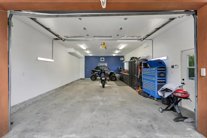 Spacious garage with a concrete floor, bright overhead lighting, and a dedicated entry door