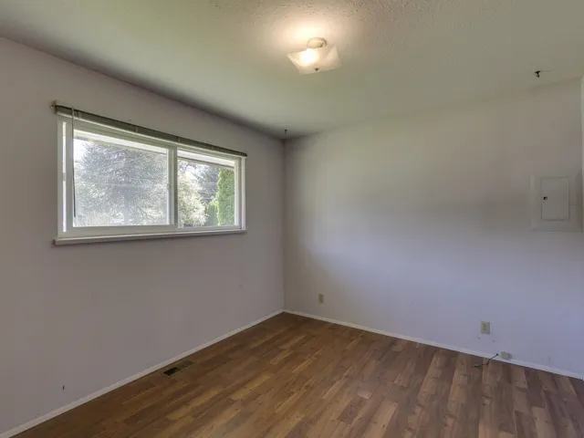Unfurnished room featuring dark wood-type flooring, electric panel, and a textured ceiling