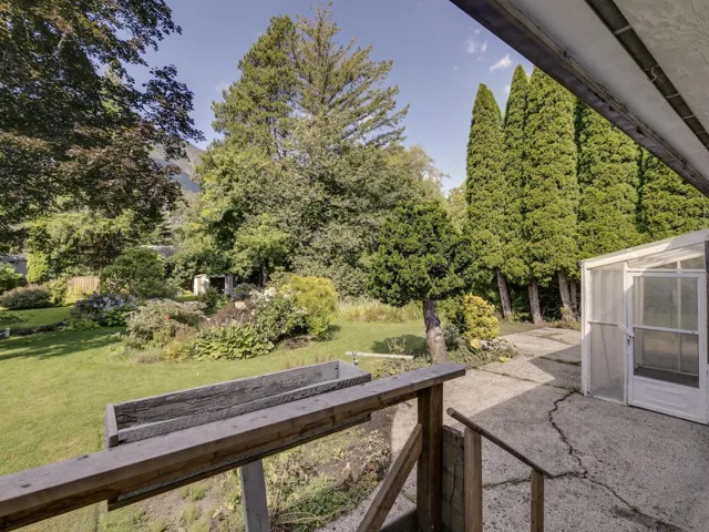 View of grassy yard featuring a greenhouse, a vegetable garden, an outbuilding, and a patio area