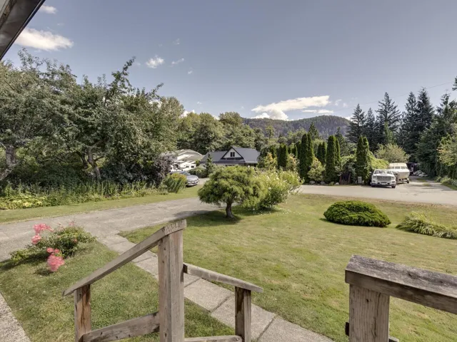 View of grassy yard featuring driveway and a forest view