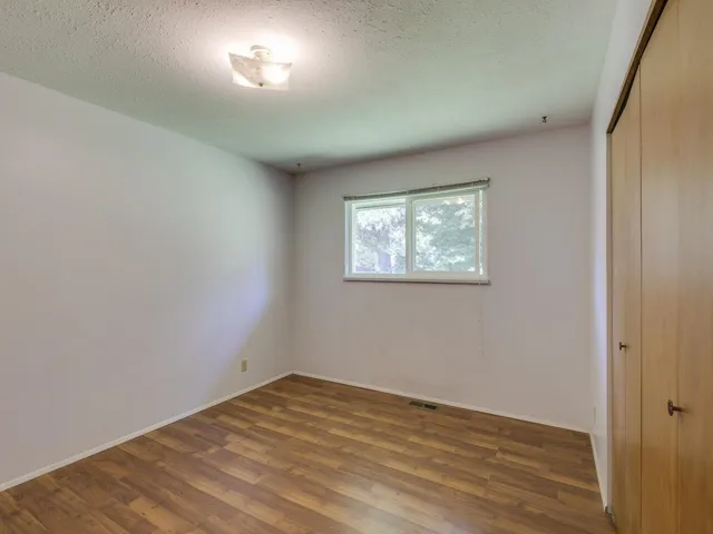 Unfurnished bedroom featuring wood finished floors, a closet, and a textured ceiling