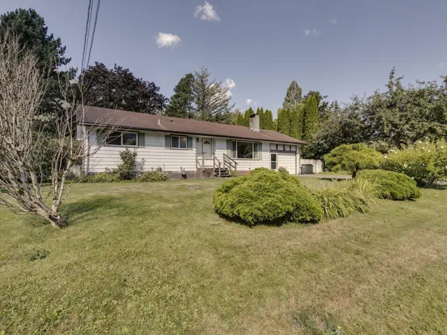 View of front of home with a front yard, a chimney, and view of wooded area