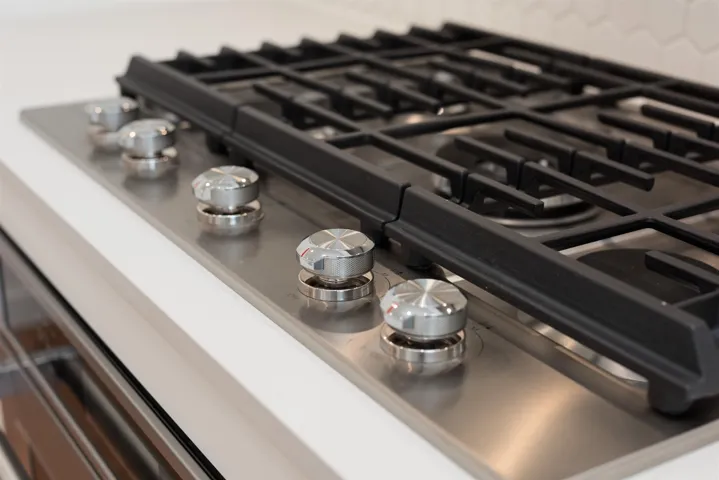 Detailed view of stainless steel gas cooktop, oven, and backsplash