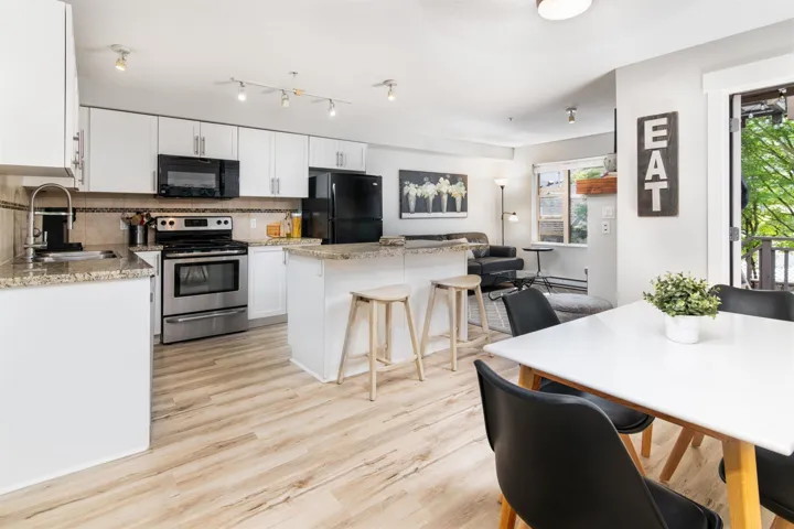 Kitchen with black appliances, a center island, backsplash, light wood-style flooring, and white cabinets