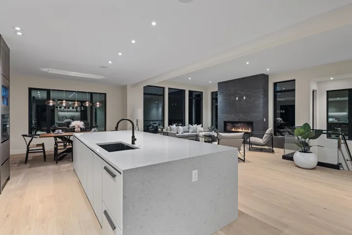 Kitchen with a premium fireplace, modern cabinets, recessed lighting, light stone counters, and light wood-style floors