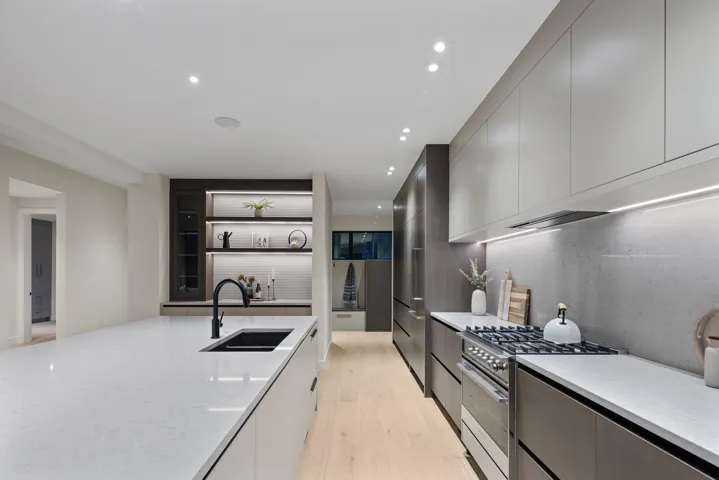 Kitchen featuring modern cabinets, high end stainless steel range oven, light wood-style floors, light stone countertops, and recessed lighting