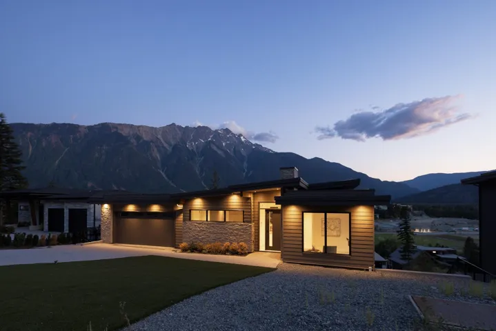 View of front facade with driveway, a mountain view, a garage, a chimney, and stone siding