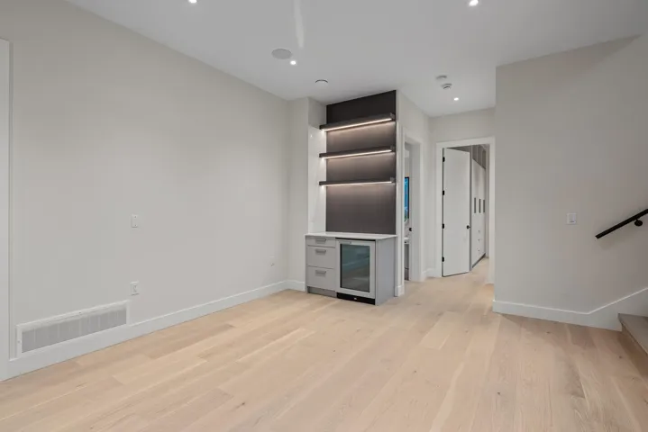 Unfurnished living room with light wood-type flooring, beverage cooler, stairs, and recessed lighting