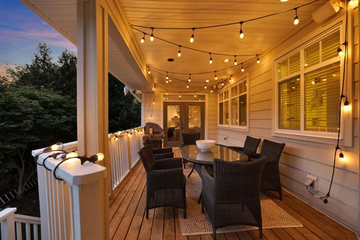 Spacious outdoor deck featuring wood-finish flooring, string lighting, and direct access through French doors
