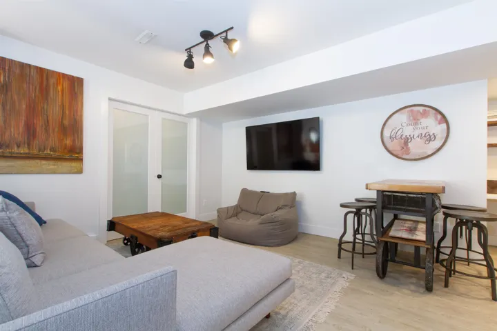 Spacious living area featuring light wood-finish flooring and track lighting