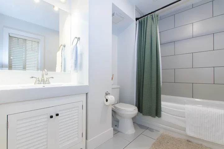 Bathroom featuring a spacious white vanity with louvered cabinetry, an integrated sink, and an expansive mirror