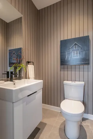 Powder room featuring vertical paneling, a wall-mounted mirror, square vessel sink with a black faucet, white vanity with black hardware, and gray floor tiling