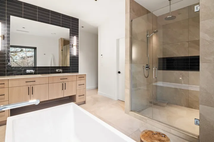 Full bath with tile patterned flooring, vanity, baseboards, a shower stall, and a tub to relax in